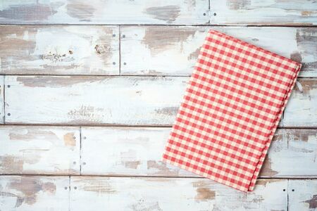 Red checked tablecloth on rustic wooden table. Kitchen, cooking or baking mock up background for design. Top view from aboveの写真素材
