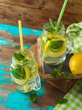 Infused water with lemon, cucumber and mint leaves over wooden background. Detox and healthy lifestyle concept.の写真素材