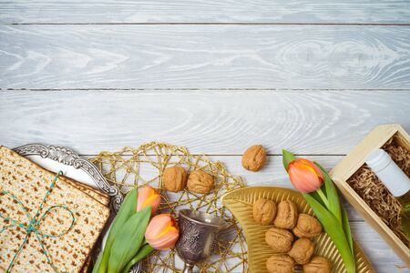Jewish holiday Passover celebration concept with seder plate, matzah and tulip flowers on wooden...