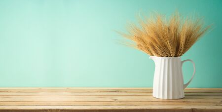 Wheat in vase on wooden table over blue background. Home decor mock up for design.の写真素材