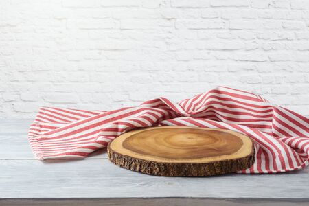 Empty wooden table with tablecloth and wooden board over white brick wall background. Kitchen mock up for designの写真素材