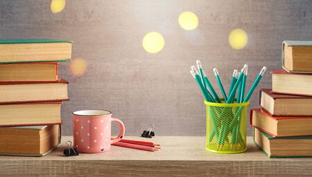 Back to school concept with coffee cup, pencils and books on wooden shelf backgroundの写真素材