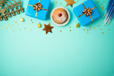 Jewish holiday Hanukkah concept with menorah, sufganiyah, gift box and spinning top over blue backgroundの写真素材