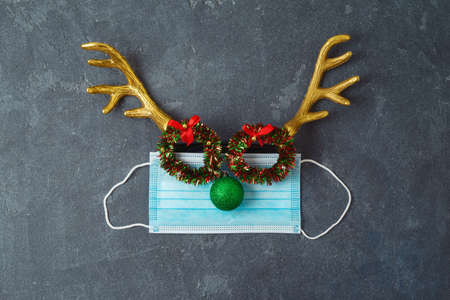 Christmas reindeer with medical face mask and party eyeglasses. Coronavirus protection minimal conceptの写真素材