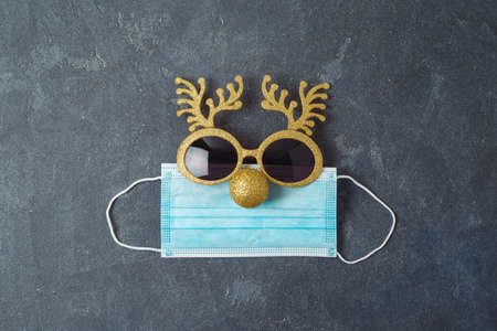 Christmas reindeer with medical face mask and party eyeglasses. Coronavirus protection minimal...
