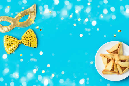 Jewish holiday Purim concept with carnival mask and hamantaschen cookies on blue background