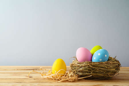 Easter holiday background with easter eggs in bird nest on wooden table