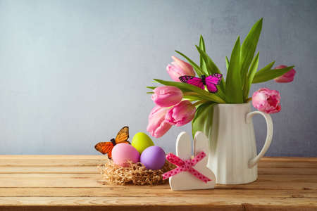 Easter holiday concept with easter eggs and tulip flowers on wooden tableの写真素材
