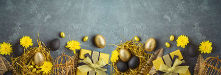 Easter holiday concept with golden Easter eggs and gift box on dark backgroundの写真素材