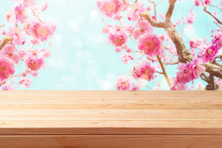 Empty wooden table over beautiful cherry blossom background. Spring and easter mock up for design