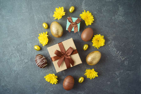 Easter holiday concept with golden Easter eggs and gift box on dark background