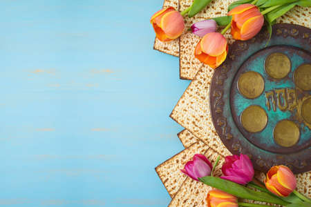 Jewish holiday Passover celebration concept with seder plate, matzah and tulip flowers on wooden table. Pesach background. Hebrew text " Passover"の写真素材