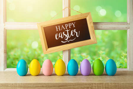 Easter holiday concept with Easter eggs decor on wooden table over window background