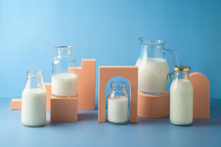Milk bottles and milk jug over blue background. Modern still life composition. Healthy eating conceptの写真素材