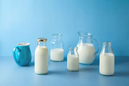 Milk bottles and milk jug over blue background. Modern still life composition. Healthy eating conceptの写真素材