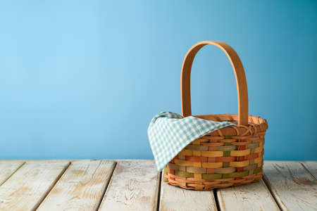 Empty basket with tablecloth on rustic wooden table over blue wall  background.  Kitchen mock up for design and product display.の写真素材