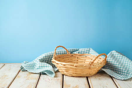 Empty wicker basket with tablecloth on rustic table over blue wall  background.  Kitchen mock up for design and product display.の写真素材