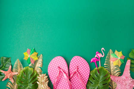 Summer holiday vacation concept with beach accessories and tropical leaves on green background