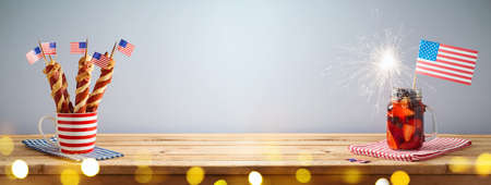 Happy Independence Day, 4th of July celebration background with summer fresh fruit drink, twisted hot dog sausages and USA flag on wooden tableの写真素材