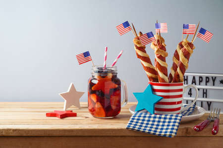 Happy Independence Day, 4th of July celebration concept with summer fresh fruit drink, twisted hot dog sausages and USA flag on wooden tableの写真素材