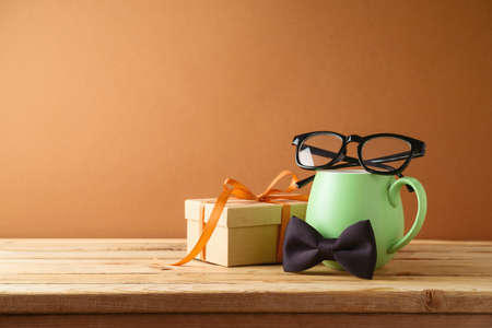 Happy Fathers day concept with green coffee cup, tie bow and gift box on wooden tableの写真素材