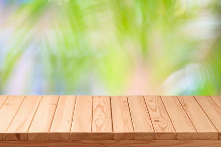 Empty wooden table over palm tree blurred background.  Summer tropical nature mock up for design and...