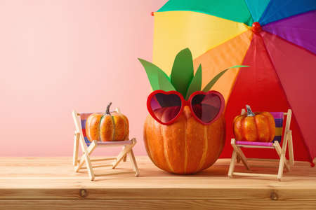 Halloween pumpkin creative decor as pineapple with sunglasses on wooden tableの写真素材