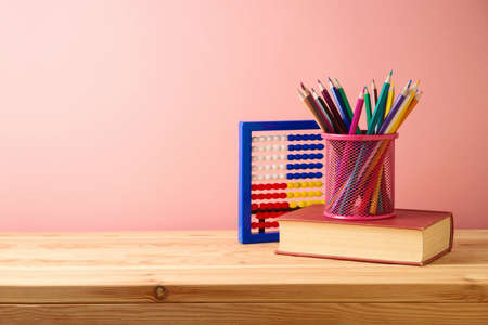 Back to school background with colorful pencils, book and rainbow on wooden table. Diversity and...