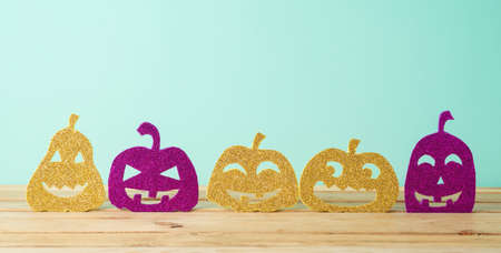 Halloween funny glitter  jack o lantern decor  on wooden table over blue backgroundの写真素材