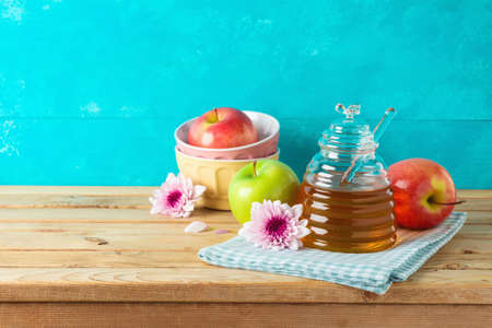 Jewish holiday Rosh Hashana concept with honey jar, apple and flowers on wooden tableの写真素材