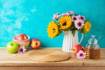 Jewish holiday Rosh Hashana background with honey jar, apples and sunflowers on wooden table. Kitchen counter for product displayの写真素材