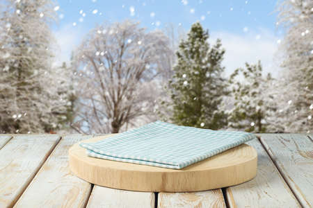 Empty wooden log with tablecloth on rustic table over winter landscape background.  Christmas and New Year mock up for design and product display.の写真素材