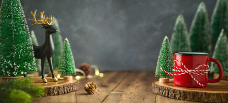 Christmas decorations on wooden table. New Year holiday banner design with coffee cup and reindeer decorの写真素材