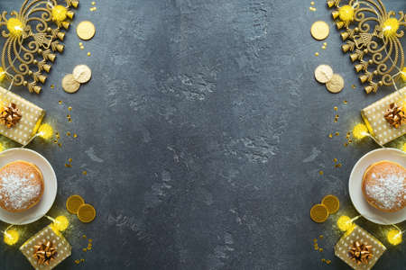 Jewish holiday Hanukkah concept with traditional donuts, menorah and gift box on dark background....