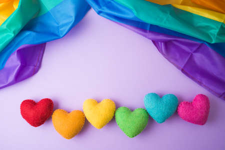 Rainbow heart shapes and rainbow flag on violet background. Happy Valentines day, inclusiveness and...