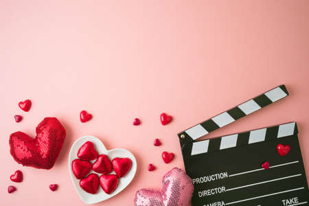 Happy Valentines day and romantic movie concept with  movie clapper board, heart shapes and chocolates on pink background. Flat lay, top viewの写真素材
