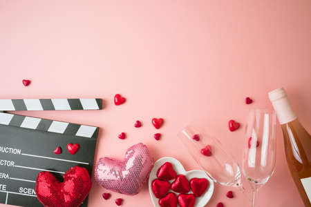 Romantic movie border frame with movie clapper board, heart shapes and wine bottle on pink background. Valentines day concept. Flat lay, top viewの写真素材