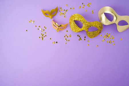 Carnival or mardi gras background with golden carnival masks on violet background. Top view with copy spaceの写真素材