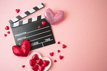 Happy Valentines day and romantic movie concept with  movie clapper board, heart shapes and chocolates on pink background. Flat lay, top viewの写真素材