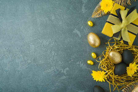 Happy Easter holiday concept with golden Easter eggs and gift box on dark background. Top view, flat...