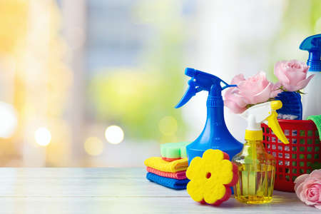 Spring cleaning concept with supplies on wooden table over beautiful bokeh backgroundの写真素材