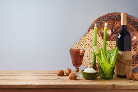 Passover holiday concept with wine, matzah and seder plate on wooden table over gray background