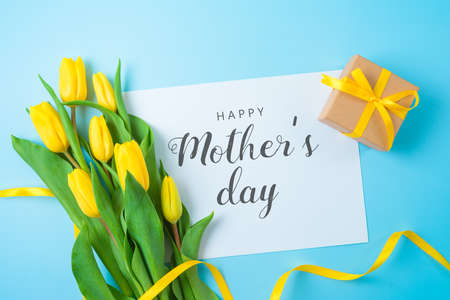 Happy Mothers day  greeting card design. Fla lay gift box and beautuful tulip flowers on blue...