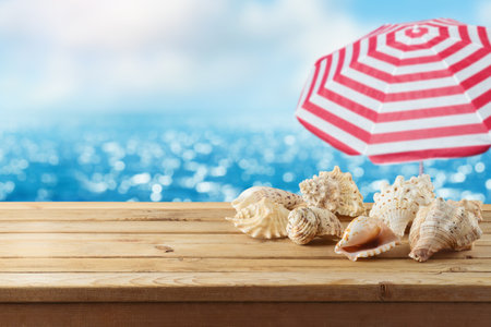 Seashells on wooden table over sea beach background.  Summer mock up for design and product display.の写真素材