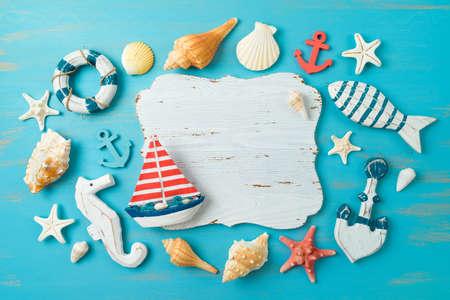 Summer beach vacation concept with wooden board, sailing boat and nautical decorations over blue background. Flat lay, top viewの写真素材