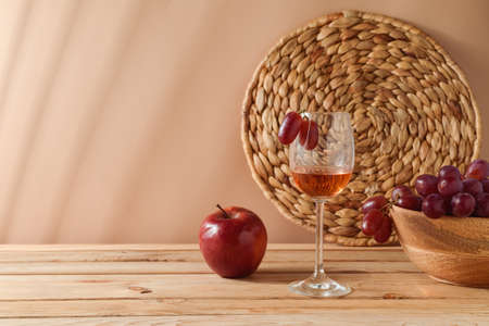 Summer still life composition with wine and grapes on wooden table over beige backgroundの写真素材