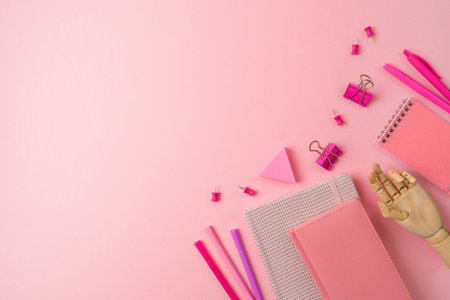 Feminine desk workplace with notebook, wooden hand and pens on pink background. Back to school concept. Top view, flat layの写真素材