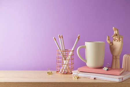 Stylish feminine home office desk with coffee cup, notebook and pencils over purple background. Back to school conceptの写真素材