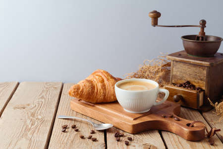 Morning breakfast concept with fresh coffee cup and croissant on wooden table. Background for coffee shop or cafeの写真素材