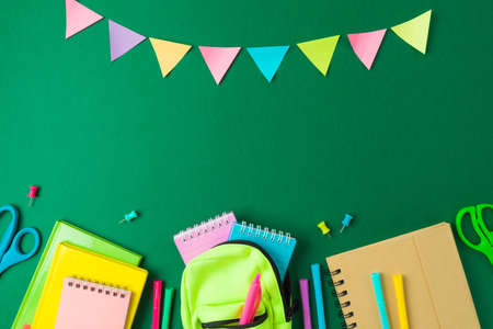 Back to school concept with school supplies and sticky notes on green background. Top view, flat lay